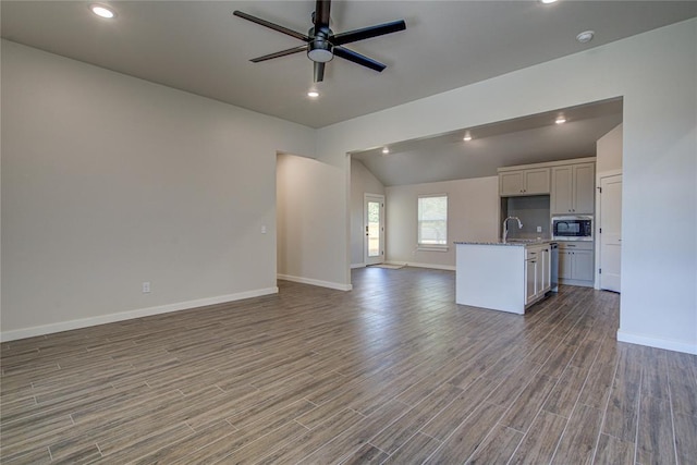 4980 12th Ave, Goldsby, OK 73093 - unfurnished living room with a ceiling fan, baseboards, vaulted ceiling, wood finished floors, and a sink