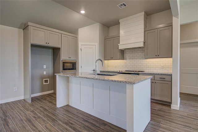 4980 12th Ave, Goldsby, OK 73093 - kitchen with a sink, gray cabinetry, custom range hood, black microwave, and a center island with sink