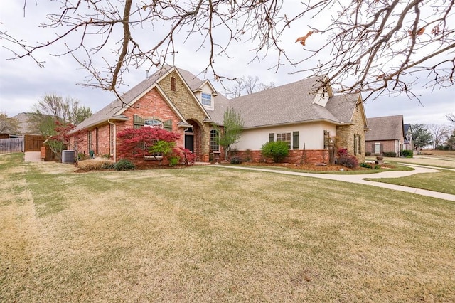 3615 S Scissortail Dr, Stillwater, OK 74074 - view of front of house with brick siding, a front yard, fence, and central AC