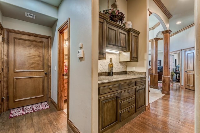 3615 S Scissortail Dr, Stillwater, OK 74074 - interior space with tasteful backsplash, ornamental molding, visible vents, ornate columns, and wood finished floors