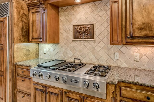 3615 S Scissortail Dr, Stillwater, OK 74074 - kitchen with tasteful backsplash, brown cabinetry, stainless steel gas cooktop, and light stone countertops