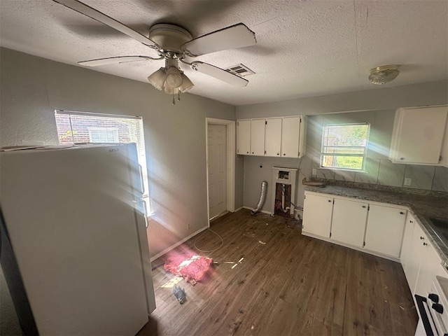 kitchen with white cabinets, freestanding refrigerator, a textured ceiling, and dark wood-style floors