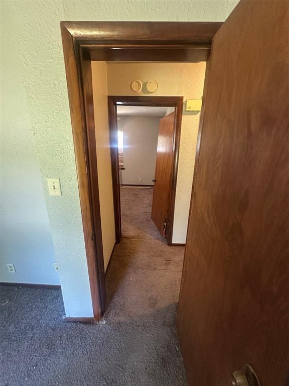 hallway with a textured wall and carpet flooring