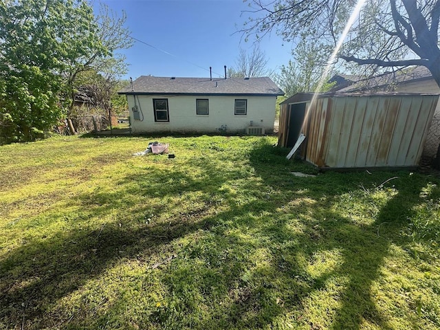 back of property with a lawn, an outbuilding, concrete block siding, and a shed