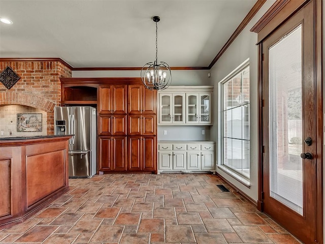 1217 Camelot Dr, Yukon, OK 73099 - kitchen with crown molding, hanging light fixtures, a chandelier, stainless steel fridge with ice dispenser, and stone finish floor