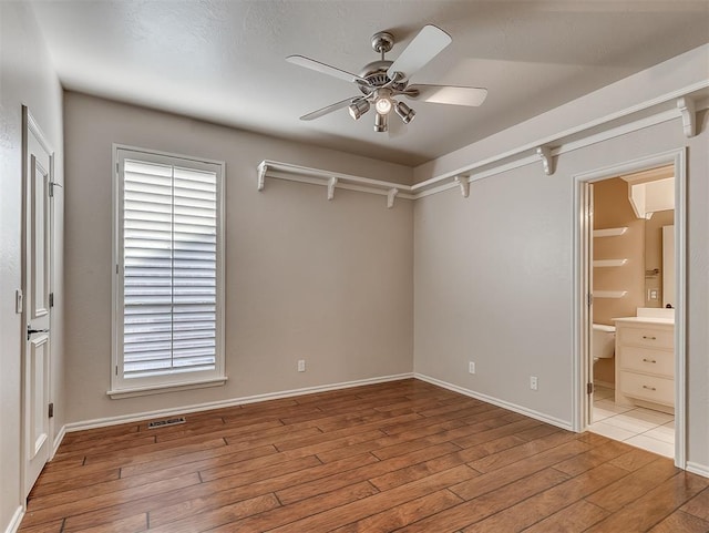 1217 Camelot Dr, Yukon, OK 73099 - unfurnished bedroom featuring visible vents, baseboards, a ceiling fan, hardwood / wood-style flooring, and ensuite bath