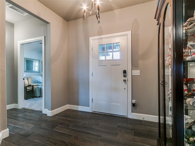 entrance foyer featuring wood finish floors, an inviting chandelier, visible vents, and baseboards