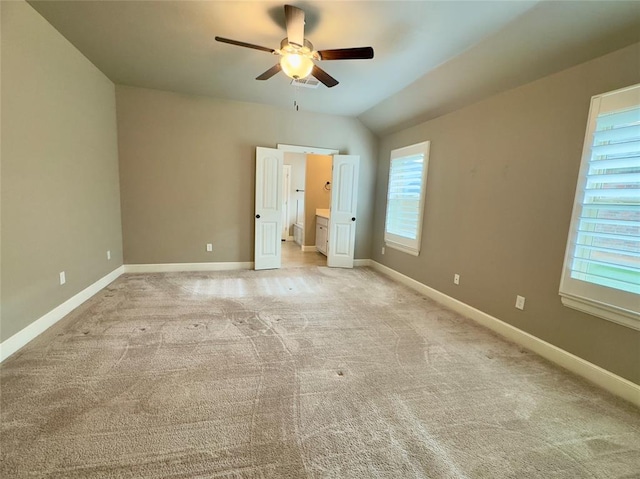 unfurnished bedroom with ceiling fan, vaulted ceiling, baseboards, and light colored carpet