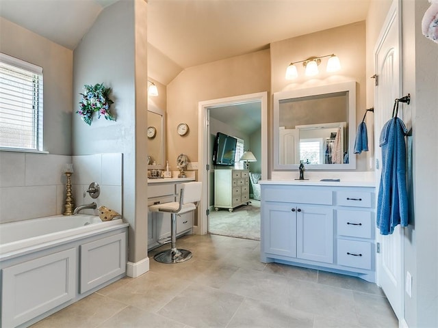 bathroom with two vanities, vaulted ceiling, and a healthy amount of sunlight
