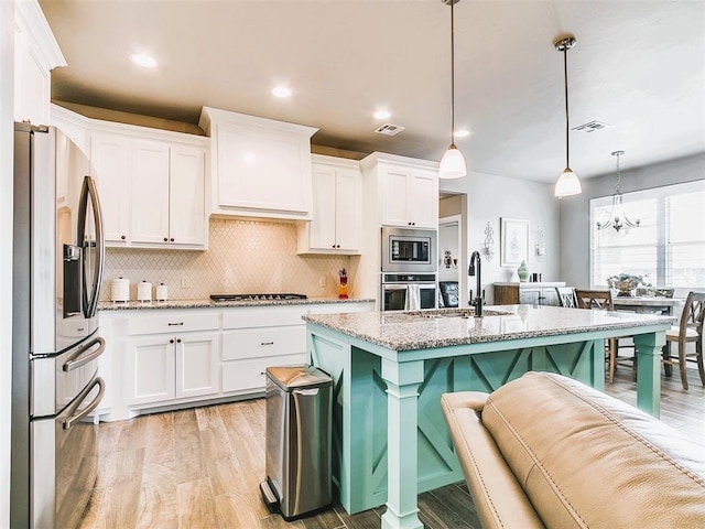 kitchen featuring a kitchen breakfast bar, a sink, white cabinetry, light stone counters, and appliances with stainless steel finishes