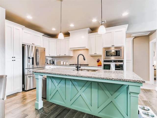 kitchen with white cabinets, appliances with stainless steel finishes, a sink, and light wood-style flooring