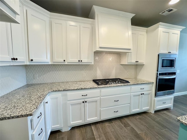 kitchen featuring white cabinets, backsplash, stainless steel appliances, and visible vents