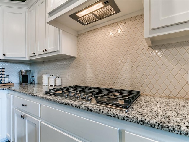 kitchen featuring white cabinets, ventilation hood, light stone counters, stainless steel gas cooktop, and tasteful backsplash