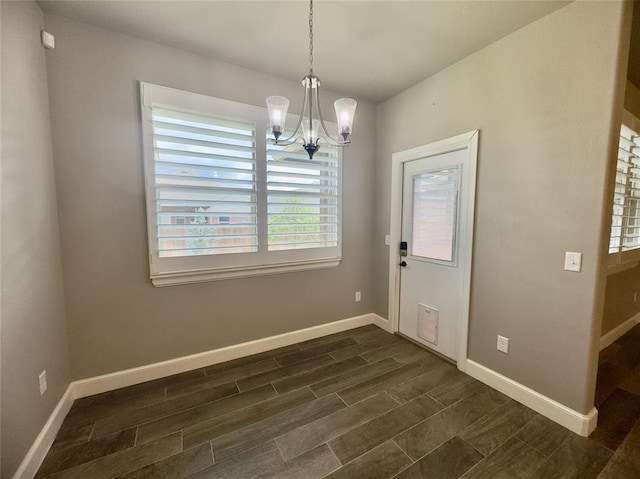interior space featuring baseboards, wood finish floors, and a notable chandelier