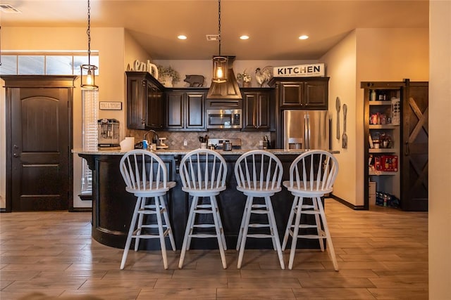 9908 SW 22nd St, Yukon, OK 73099 - kitchen with stainless steel appliances, a kitchen bar, dark brown cabinetry, light wood finished floors, and recessed lighting