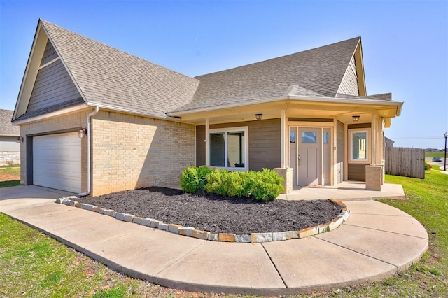 view of front of property with a shingled roof, fence, a front lawn, brick siding, and driveway