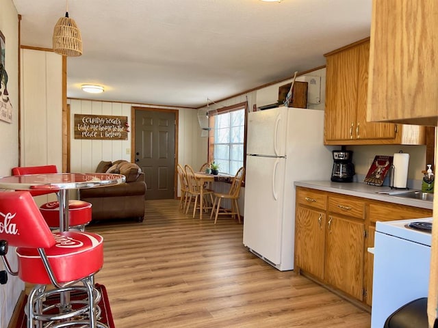 kitchen featuring white appliances, light wood-style flooring, brown cabinetry, light countertops, and a sink