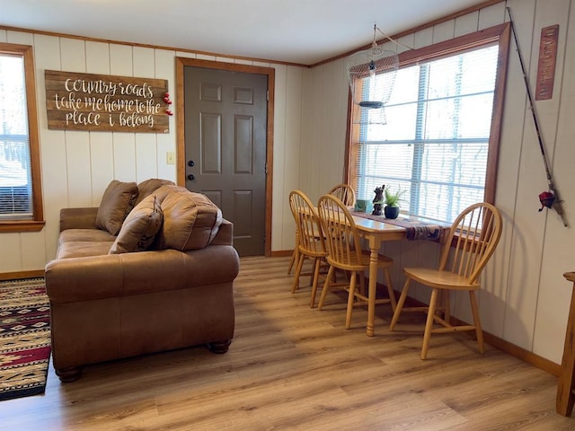 living area with crown molding, baseboards, and light wood-type flooring