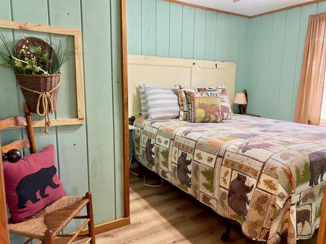 bedroom with ornamental molding and wood finished floors