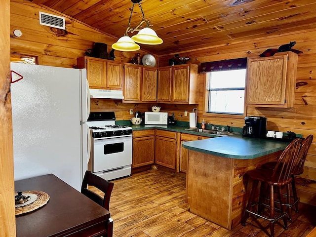 kitchen with visible vents, a sink, white appliances, a peninsula, and under cabinet range hood