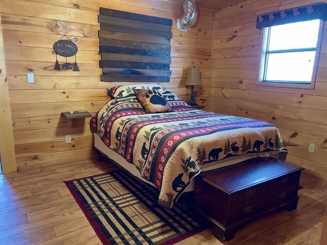 bedroom with wood walls and wood finished floors