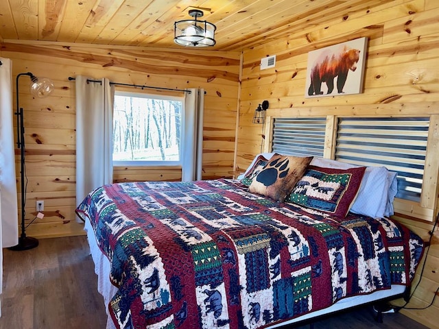 bedroom featuring wooden walls, visible vents, wooden ceiling, and wood finished floors