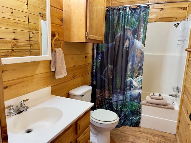full bathroom featuring toilet, wood finished floors, wood walls, and vanity