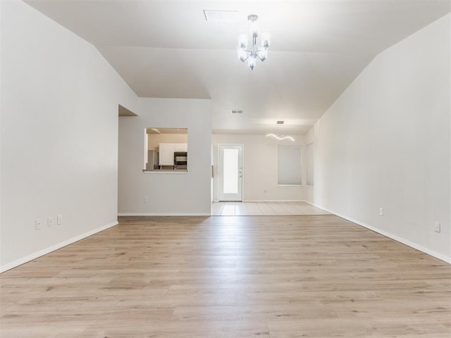 1801 NW 145th St, Edmond, OK 73013 - unfurnished living room featuring an inviting chandelier, light wood-style flooring, baseboards, lofted ceiling, and visible vents