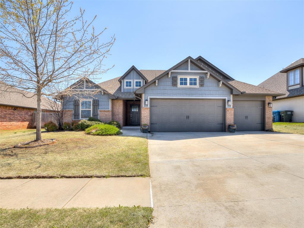 craftsman inspired home with brick siding, an attached garage, driveway, and a front lawn