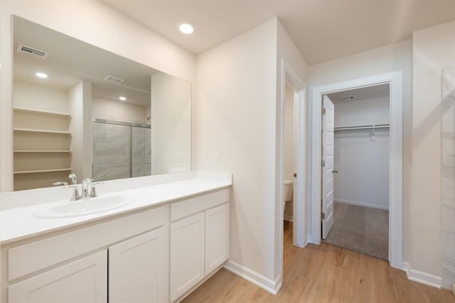 2416 Kathleens Xing, Yukon, OK 73099 - full bath with vanity, a stall shower, a walk in closet, wood finished floors, and recessed lighting