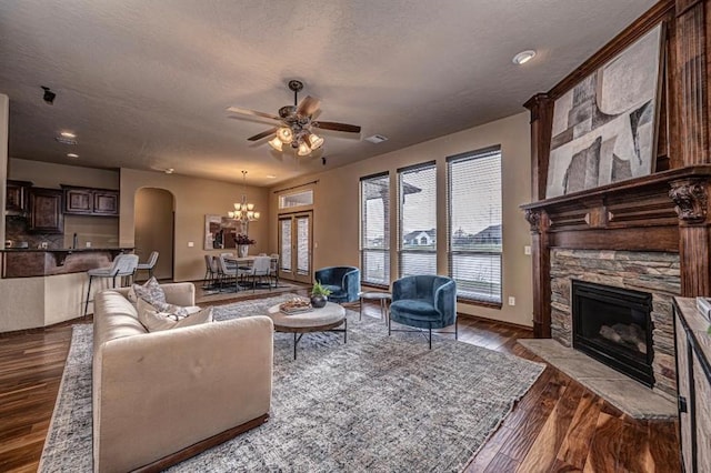 9609 Lakecrest Dr, Oklahoma City, OK 73159 - living room featuring ceiling fan with notable chandelier, a fireplace, arched walkways, a textured ceiling, and dark wood-style floors