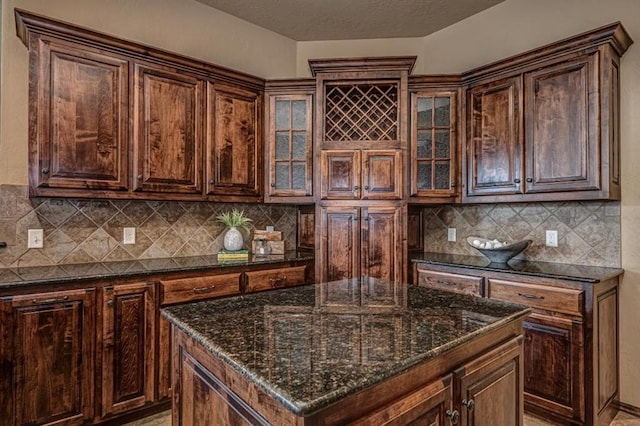 9609 Lakecrest Dr, Oklahoma City, OK 73159 - kitchen with dark stone countertops, glass insert cabinets, dark brown cabinets, a kitchen island, and decorative backsplash
