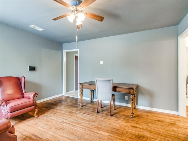 interior space with visible vents, baseboards, a ceiling fan, and wood finished floors