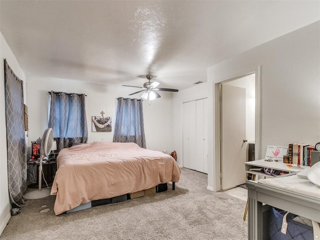 bedroom with a closet, visible vents, a ceiling fan, and light carpet