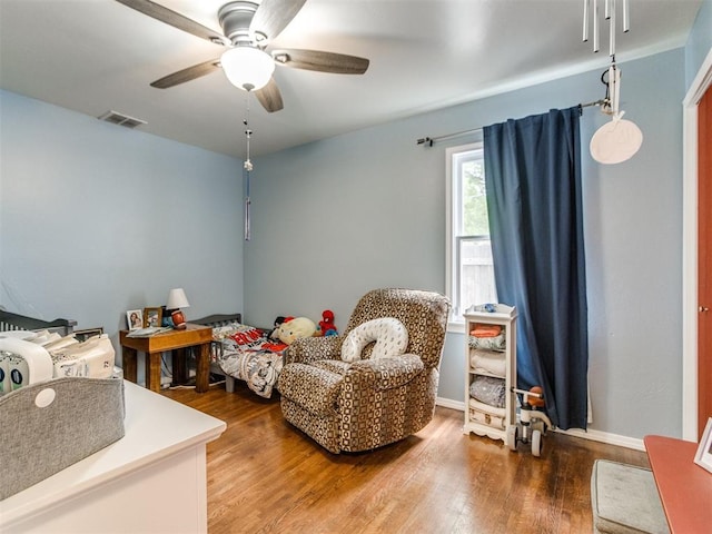 sitting room with wood finished floors, visible vents, and a ceiling fan