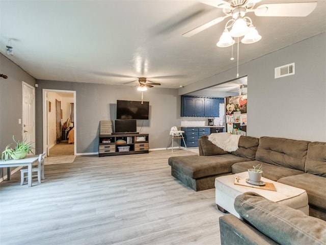 living room featuring baseboards, light wood-style flooring, visible vents, and ceiling fan