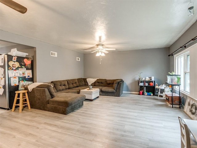 living area with visible vents, light wood finished floors, and ceiling fan