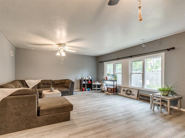 living area featuring light wood-type flooring, baseboards, and ceiling fan