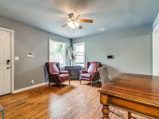 living area featuring light wood-type flooring, baseboards, visible vents, and ceiling fan