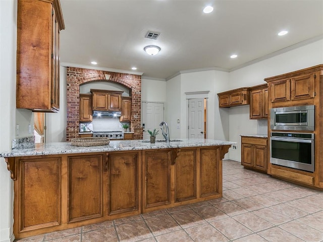 9333 SW 22nd St, Oklahoma City, OK 73128 - kitchen with light stone counters, under cabinet range hood, stainless steel appliances, and a sink