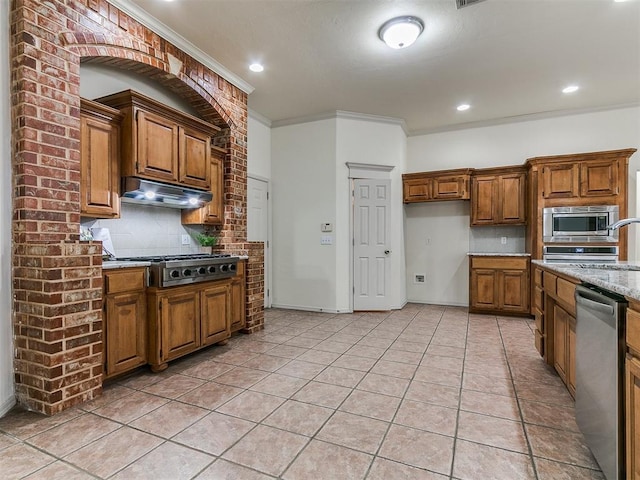 9333 SW 22nd St, Oklahoma City, OK 73128 - kitchen with stainless steel appliances, backsplash, brown cabinets, under cabinet range hood, and ornamental molding