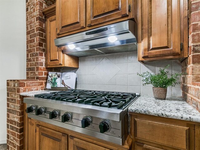 9333 SW 22nd St, Oklahoma City, OK 73128 - kitchen with stainless steel gas stovetop, tasteful backsplash, brown cabinets, and under cabinet range hood