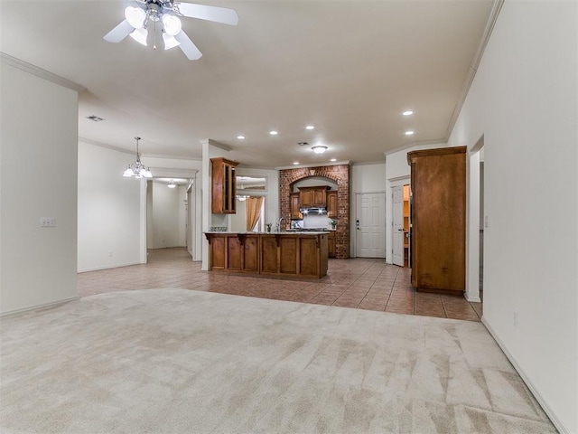 9333 SW 22nd St, Oklahoma City, OK 73128 - kitchen featuring crown molding, brown cabinets, ceiling fan, light carpet, and a peninsula