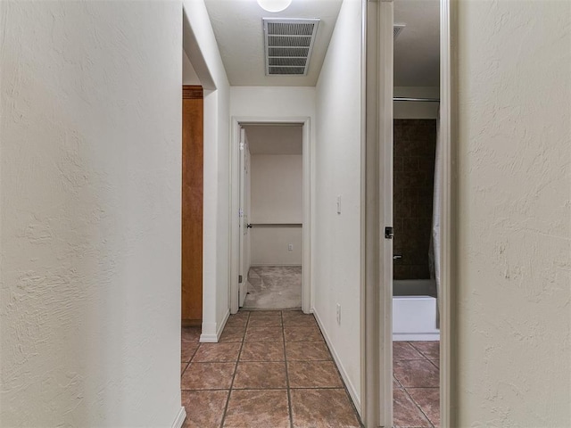 9333 SW 22nd St, Oklahoma City, OK 73128 - hall featuring dark tile patterned floors, a textured wall, visible vents, and baseboards