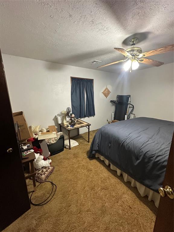 bedroom featuring a textured ceiling, a ceiling fan, and carpet floors