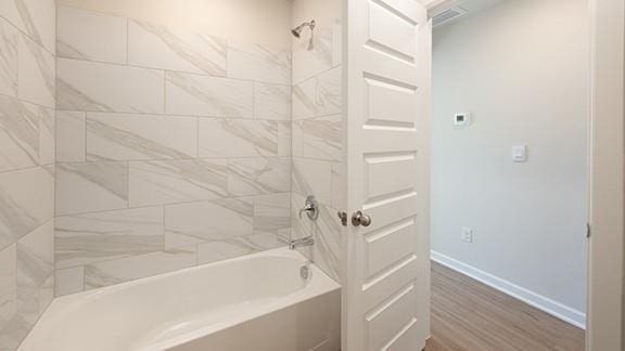 1209 E Stetson Ln, Mustang, OK 73064 - bathroom with wood finished floors, baseboards, and shower / washtub combination