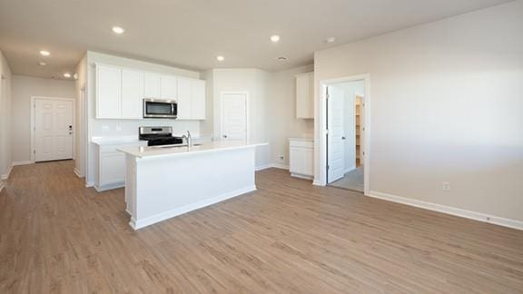 1209 E Stetson Ln, Mustang, OK 73064 - kitchen featuring stainless steel appliances, light wood-style floors, and white cabinetry