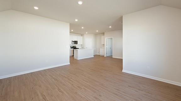 1209 E Stetson Ln, Mustang, OK 73064 - unfurnished living room featuring recessed lighting, baseboards, vaulted ceiling, and wood finished floors