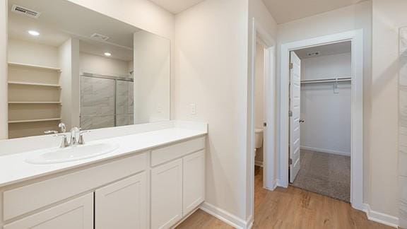 1209 E Stetson Ln, Mustang, OK 73064 - bathroom featuring a stall shower, wood finished floors, vanity, and visible vents
