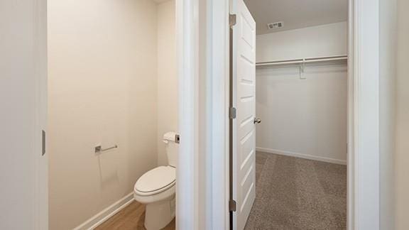 1209 E Stetson Ln, Mustang, OK 73064 - bathroom with visible vents, toilet, a walk in closet, and baseboards